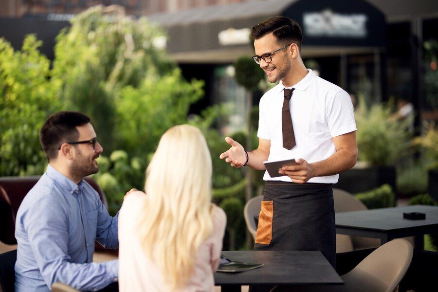 young-smiling-waiter-using-digital-tablet-while-communicating-with-couple-outdoor-cafe_637285-557.jpg